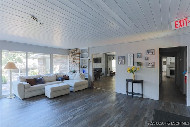 living area with wood walls, dark wood finished floors, a fireplace, and wood ceiling