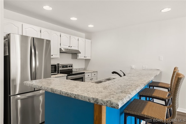 kitchen featuring a sink, stainless steel appliances, white cabinetry, a peninsula, and under cabinet range hood