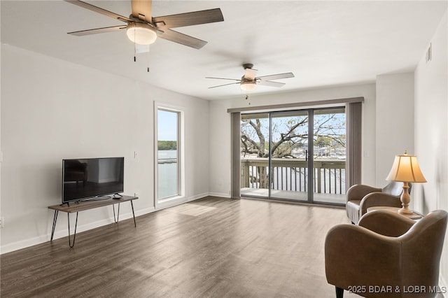 living area featuring visible vents, a ceiling fan, baseboards, and wood finished floors