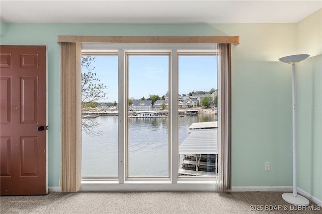 doorway featuring carpet floors, baseboards, and a water view