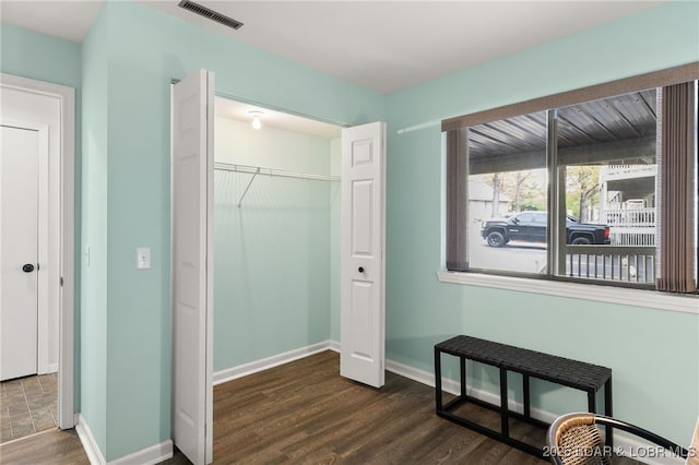 interior space with visible vents, baseboards, dark wood-style floors, and a closet