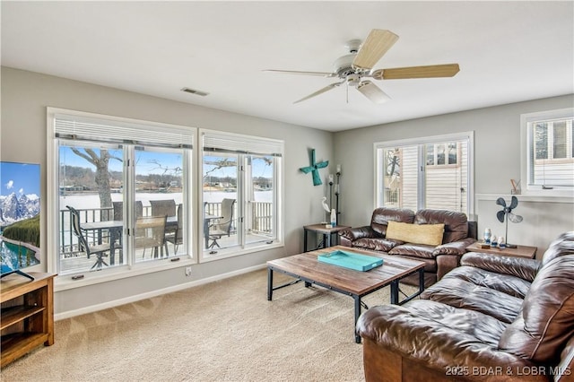 carpeted living area featuring baseboards, visible vents, and a ceiling fan