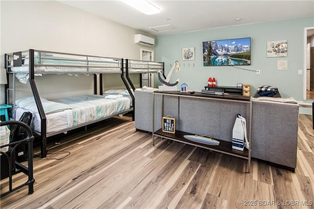 bedroom with attic access, an AC wall unit, and wood finished floors