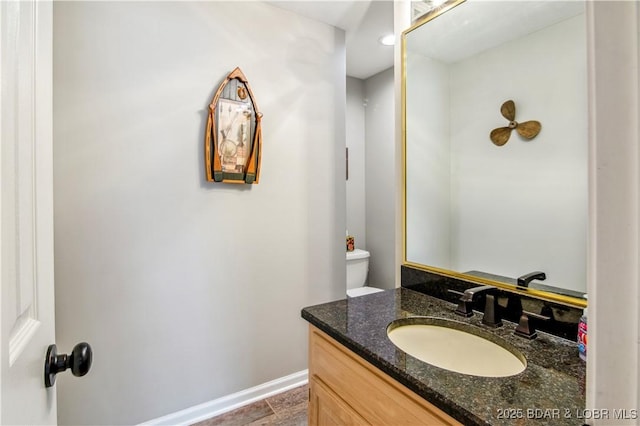 half bath with baseboards and vanity