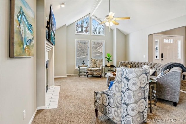 carpeted living room with beam ceiling, a tiled fireplace, a ceiling fan, high vaulted ceiling, and baseboards