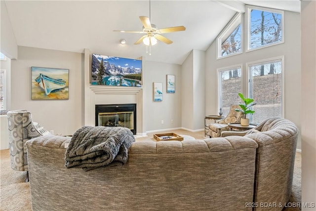 carpeted living area featuring beam ceiling, a ceiling fan, a glass covered fireplace, high vaulted ceiling, and baseboards