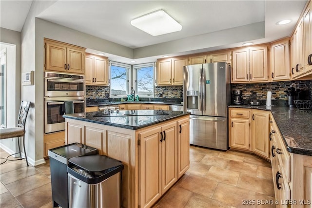 kitchen featuring decorative backsplash, a kitchen island, appliances with stainless steel finishes, light brown cabinets, and a sink