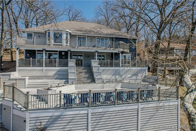 back of house with stairway, a balcony, and a pool