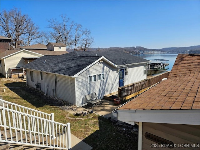 view of property exterior with a shingled roof and a water and mountain view