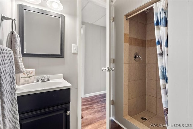 bathroom featuring wood finished floors, tiled shower, and vanity