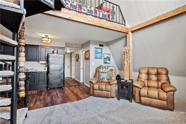 living area featuring wooden walls, visible vents, dark wood finished floors, dark colored carpet, and beam ceiling