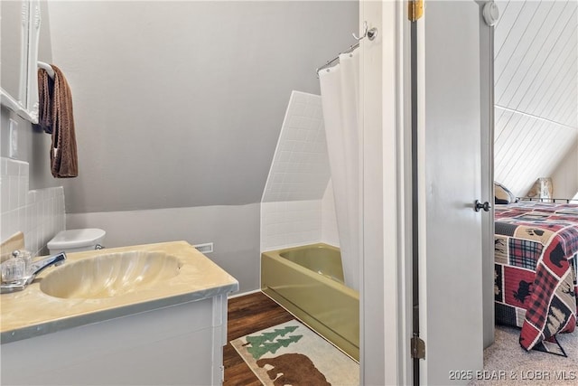 ensuite bathroom featuring wood finished floors, vanity, visible vents, vaulted ceiling, and ensuite bath