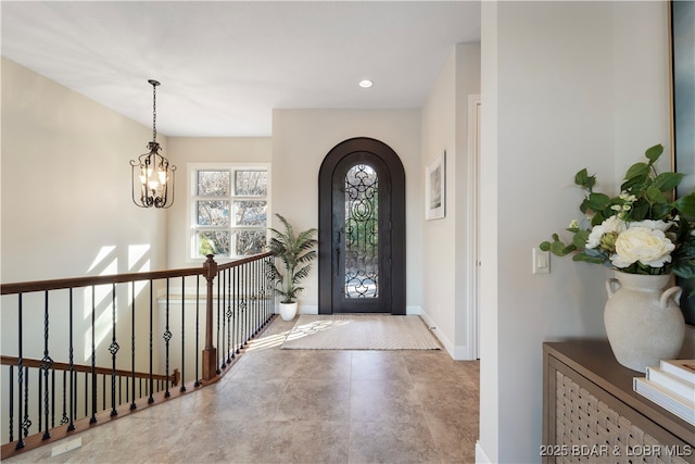 entryway featuring arched walkways, a chandelier, recessed lighting, and baseboards