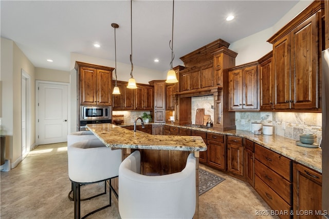 kitchen featuring hanging light fixtures, light stone counters, tasteful backsplash, and appliances with stainless steel finishes