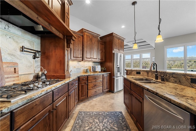 kitchen featuring tasteful backsplash, light stone counters, hanging light fixtures, stainless steel appliances, and a sink