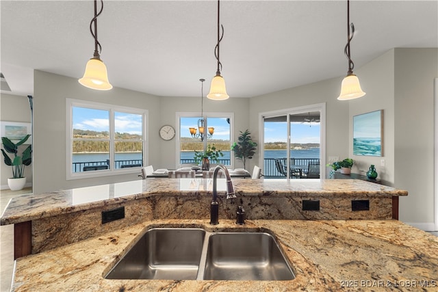 kitchen featuring a sink, light stone counters, and pendant lighting