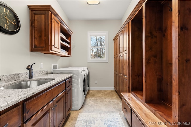 laundry room featuring washing machine and clothes dryer, cabinet space, baseboards, and a sink