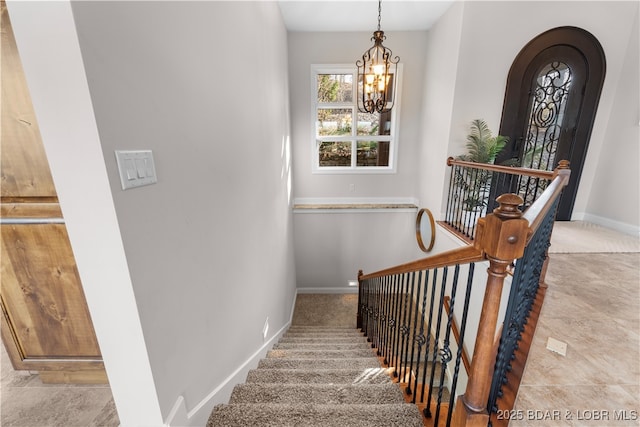 stairway featuring baseboards, arched walkways, and an inviting chandelier