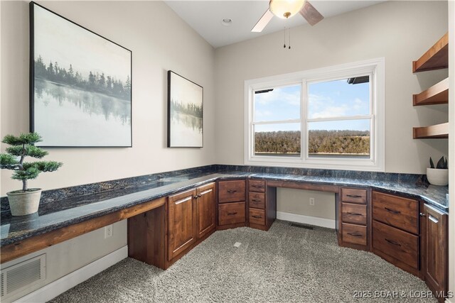 unfurnished office with built in desk, visible vents, and a ceiling fan