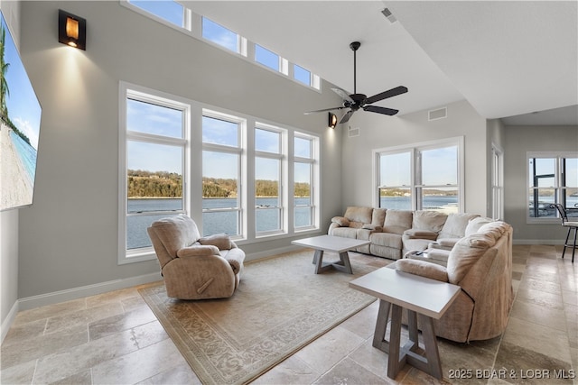 living area featuring baseboards, a healthy amount of sunlight, visible vents, and stone tile flooring