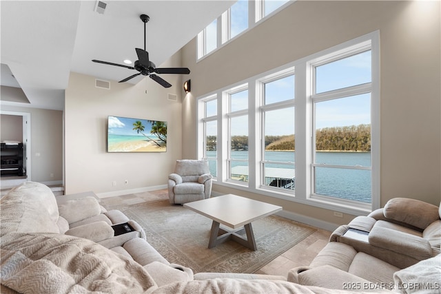 living area featuring a towering ceiling, baseboards, visible vents, and a wealth of natural light