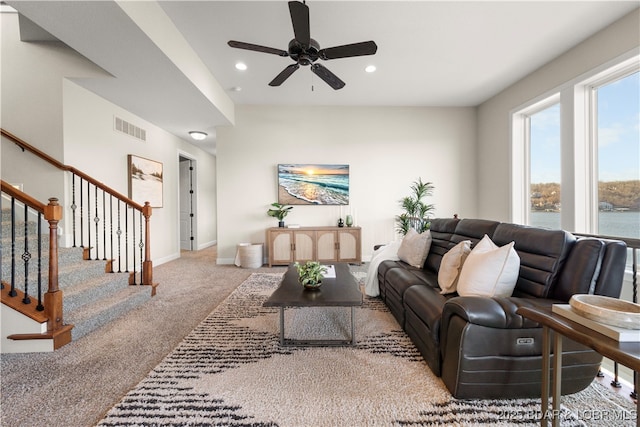 carpeted living area featuring a ceiling fan, visible vents, baseboards, recessed lighting, and stairs