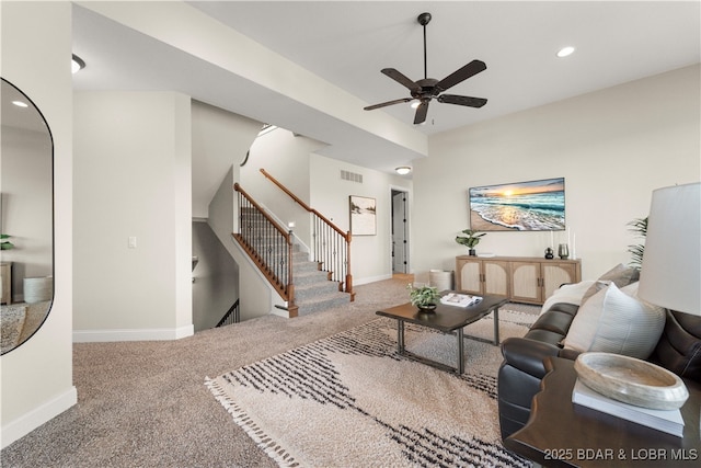 carpeted living area featuring a ceiling fan, visible vents, baseboards, recessed lighting, and stairs