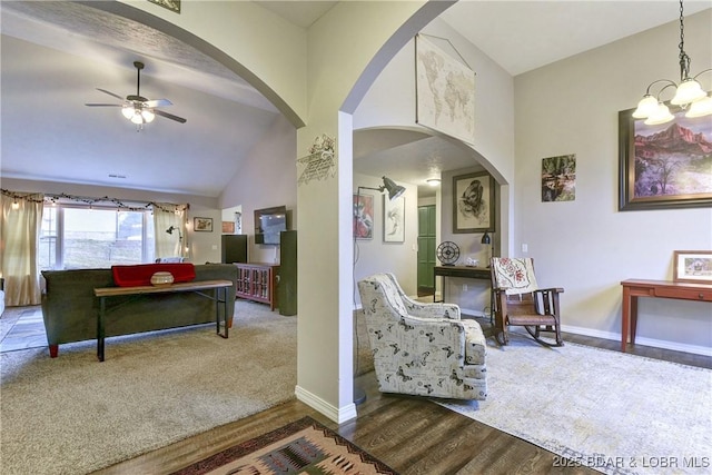 living area with carpet floors, baseboards, wood finished floors, and ceiling fan with notable chandelier