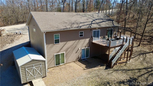 rear view of house with roof with shingles, stairway, and a wooden deck