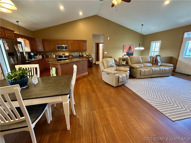 dining room featuring high vaulted ceiling, dark wood-type flooring, and ceiling fan with notable chandelier