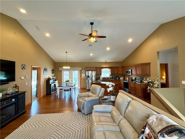 living area featuring high vaulted ceiling, recessed lighting, dark wood-style flooring, and ceiling fan with notable chandelier