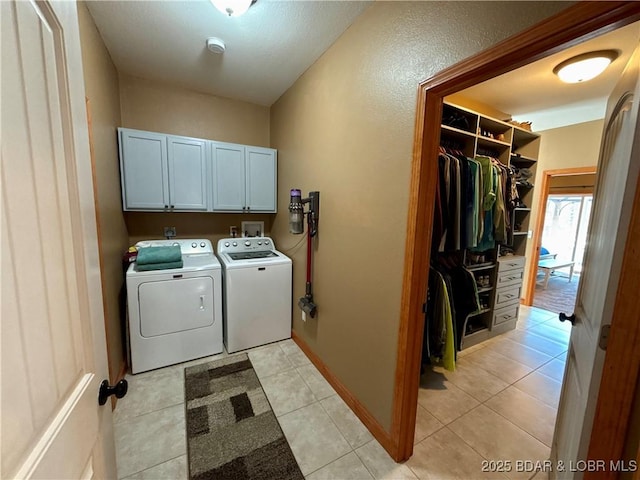 laundry area featuring washer and dryer, cabinet space, baseboards, and light tile patterned floors