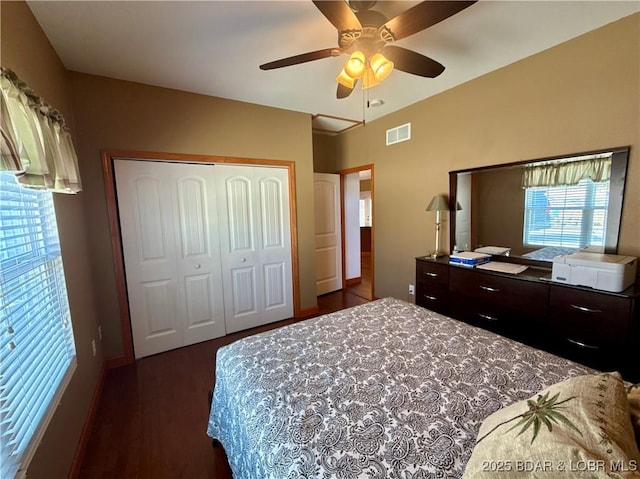 bedroom with dark wood-style floors, a closet, visible vents, and ceiling fan