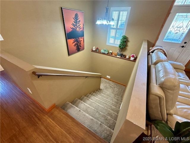 staircase featuring an inviting chandelier and baseboards