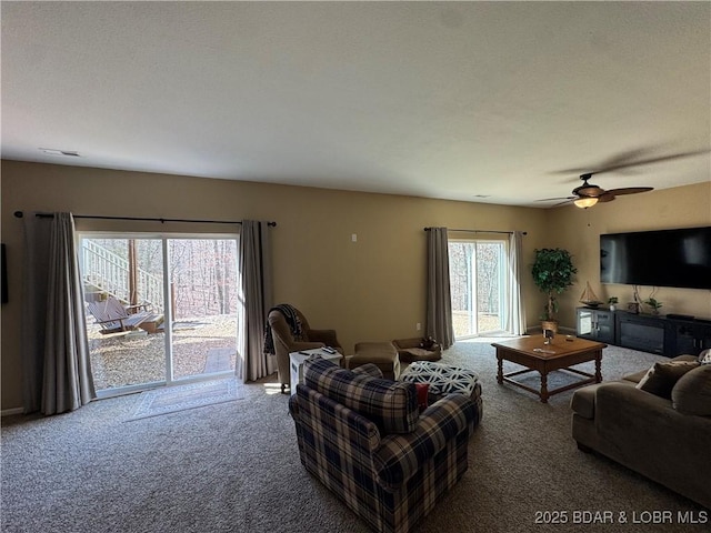 carpeted living room with ceiling fan and visible vents