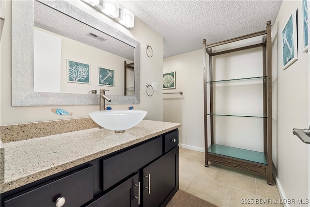 bathroom featuring visible vents, a textured ceiling, vanity, baseboards, and tile patterned floors