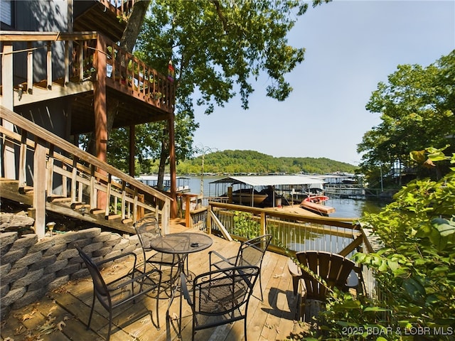 deck with a water view, stairs, and a floating dock