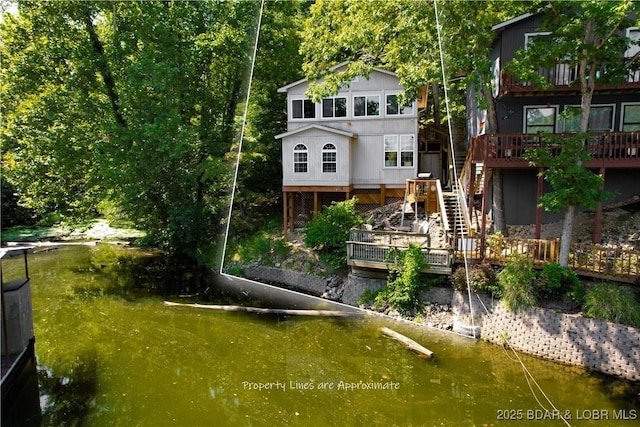 back of property with stairway and a deck with water view