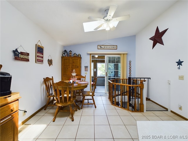 dining room with a ceiling fan, visible vents, baseboards, light tile patterned flooring, and lofted ceiling with skylight