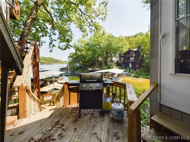 wooden deck featuring a grill, a water view, and a boat dock