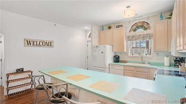 kitchen featuring light brown cabinets, a sink, wood finished floors, white appliances, and light countertops