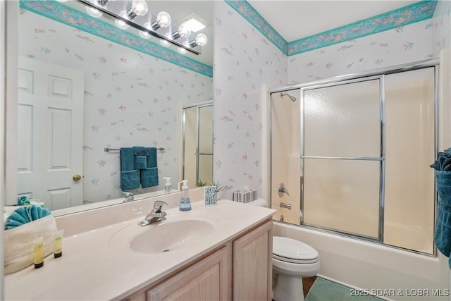 full bath featuring combined bath / shower with glass door, toilet, vanity, and wallpapered walls