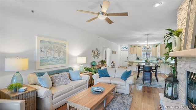 living area featuring light wood-style flooring, recessed lighting, a fireplace, and ceiling fan