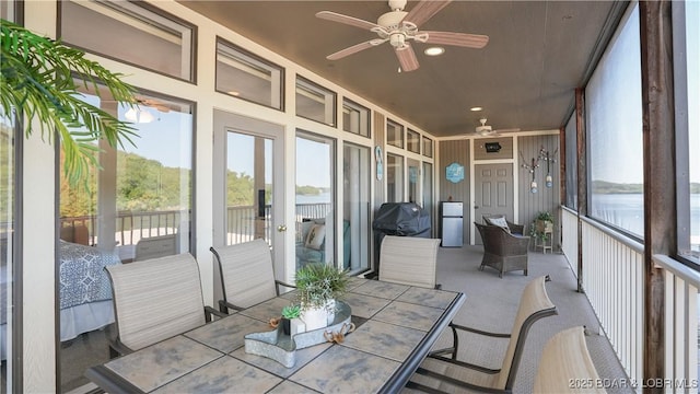 sunroom featuring a water view and ceiling fan