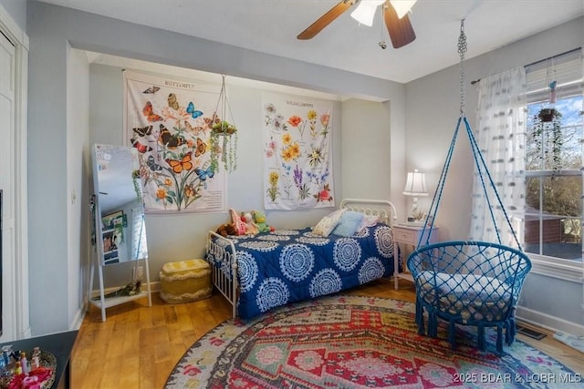 bedroom featuring visible vents, baseboards, a ceiling fan, and wood finished floors