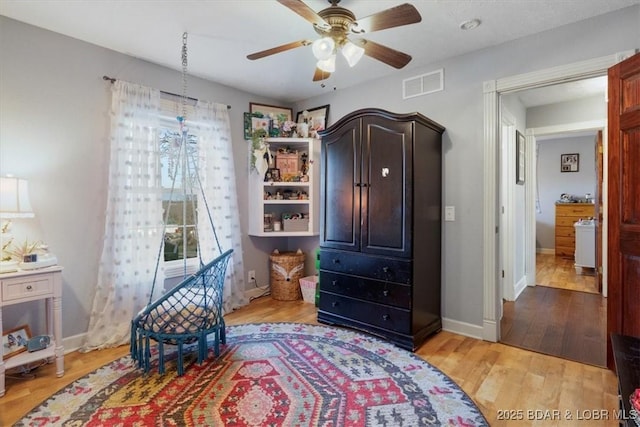 bedroom with ceiling fan, visible vents, baseboards, and wood finished floors