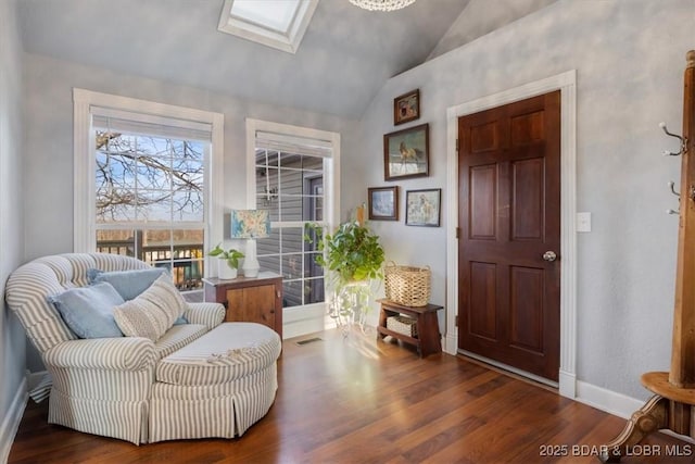 living area featuring baseboards, lofted ceiling with skylight, visible vents, and wood finished floors