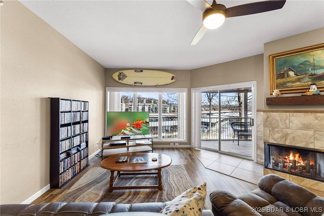 living room with wood finished floors, a fireplace, baseboards, and ceiling fan