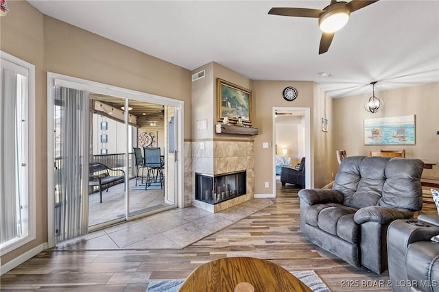 living area featuring visible vents, plenty of natural light, a tile fireplace, and wood finished floors