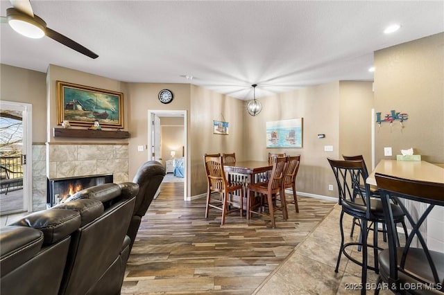 dining room with a tiled fireplace, wood finished floors, recessed lighting, baseboards, and ceiling fan